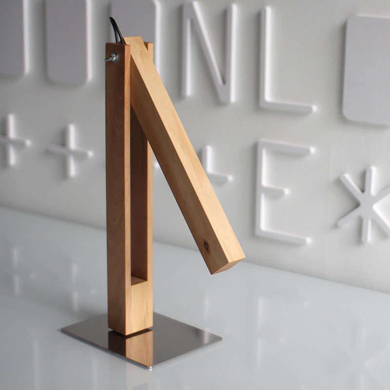 La lámpara de mesa CARFI en una Lámpara Led de Mesa fabricada en madera de aliso y luminaria led con sensor táctil y regulador de intensidad. Con una altura de 40cm y totalmente orientable en cualquier posición.